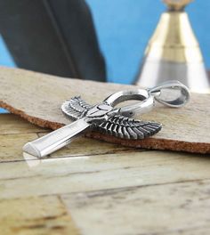 a cross with an eagle on it sitting on a piece of wood next to a pen