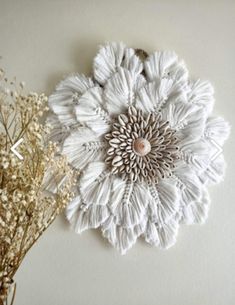 a white flower is hanging on the wall next to some dried plants and flowers in vases