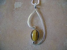 A unique 10x14mm cabochon of Tiger's eye hand bezel set in fine silver. The traditional setting is hand forged Argentium sterling silver, that suspends and frames the stone. All surfaces are hand polished to a mirror finish, no excess solder anywhere. A fine handcrafted piece that is stamped Sterling, and Hallmarked on the back. Comes with a 18" chain. Overall height 2" width 7/8" Sterling Silver Teardrop Necklace With Bezel Setting, Handmade Sterling Silver Teardrop Gemstones, Handmade Teardrop Sterling Silver Gemstones, Oval Sterling Silver Gemstones With Polished Finish, Sterling Silver Teardrop Pendant Jewelry With Polished Finish, Sterling Silver Teardrop Pendant With Polished Finish, Handmade Sterling Silver Oval Pendant Gemstone, Unique Polished Silver Gemstones, Silver Teardrop Pendant Jewelry With Bezel Setting