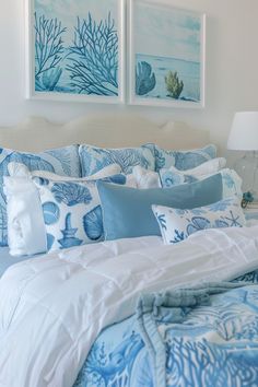 a bed with blue and white comforters in a bedroom next to two pictures on the wall