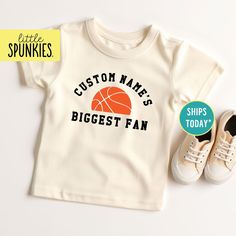 Retro Basketball Fan Tshirt, Custom Name's Biggest Fan Natural Shirt, Kids Graphic Tees (BIGGEST FAN BASKETBALL) PRODUCTION TIME Little Spunkies from the designer/owner of Spunky Pineapple Co https://www.etsy.com/shop/SpunkyPineappleCo   All baby and toddler clothes are 100% designed and printed with water based ink. All orders placed before 12:00 pm EST are shipped out same day (Monday - Friday). Orders received after noon are shipped out the next business day. ONESIES® BRAND Made from 100% Cotton. We print on Onesies® Brand. T-SHIRT Made from 100% Cotton. These run true to size. If you are in between sizes we suggest sizing up. CARE Machine wash in cold water, inside out, and tumble dry.   SHIPPING All orders are shipped out via USPS First Class Mail (3-4 days).   Shipping upgrades are a Tshirt Custom, Retro Basketball, Basketball Fans, Kids Graphic Tees, Baby And Toddler, Toddler Clothes, Monday Friday, Toddler Outfits, Baby Toddler