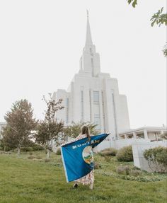 a woman holding a blue flag in front of a large building with a steeple