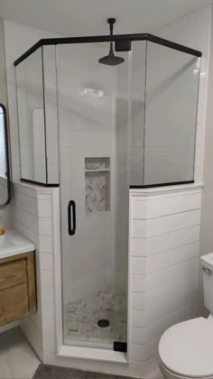 a bathroom with a toilet, sink and shower stall in white tile on the floor