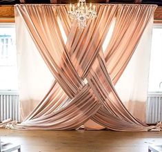 a room with a chandelier hanging from the ceiling and curtains draped over it