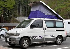 a white van with a blue tarp on top parked in a parking lot