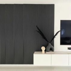 a flat screen tv sitting on top of a white cabinet next to a wall mounted television