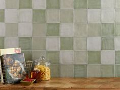 a wooden table topped with a basket filled with food next to a wall covered in tiles