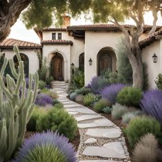 a house that is surrounded by trees and plants in front of the house with purple flowers