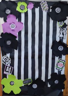 a black and white striped bulletin board with paper flowers on the front, and stickers on the back