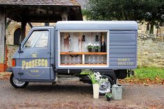 an old blue van is parked in front of a building with potted plants on the side