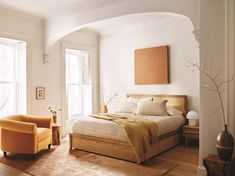 a bed sitting in a bedroom next to two chairs on top of a hard wood floor