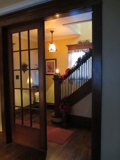 an open door leading to a living room with stairs and potted plants on the ledge