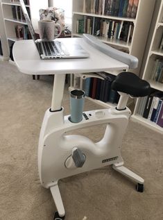 a white desk with a laptop on it in front of a bookshelf full of books