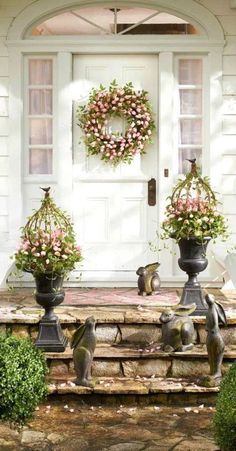 two vases filled with flowers sitting on steps in front of a white door and wreath