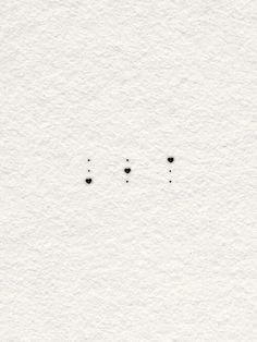 three black dots on white paper with one small dot in the middle and two smaller dots at the bottom