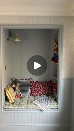 a window seat with pillows on it in a room that is painted gray and white