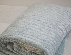 a blue blanket is folded on top of a white bed sheet and the sheets are rolled down