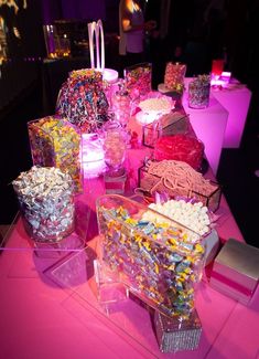 a table topped with lots of candy and candies on top of pink cloth covered tables