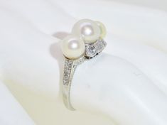 "This exquisite little treasure features 3 luscious white pearls surrounded by 14 small old European and old mine cut diamonds . Set in 18K white gold. The ring is a size 6.75. Setting measures approx. 1/2\" tall. This ring is in excellent pre-owned vintage condition. Total weight is approx. 4.8 grams. (T8 * MJP038283) Please review all photos before purchasing and feel free to ask questions about the item :) For more information you can call us at 360-657-5276. We are sorry but we do NOT offer Elegant Three Stone Pearl Ring For Anniversary, Heirloom White Gold Pearl Ring With Rose Cut Diamonds, Heirloom White Diamond Pearl Ring, Heirloom White Pearl Ring With Rose Cut Diamonds, Classic Pearl Ring With Diamonds For Anniversary, Classic Pearl Ring With Single Cut Diamonds For Wedding, Classic White Pearl Ring With Rose Cut Diamonds, Vintage White Gold Pearl Ring With Diamond Accents, White Pearl Ring With Rose Cut Diamonds For Anniversary