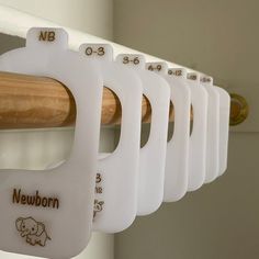 a row of baby bibs hanging from a wooden rail with numbers on the side