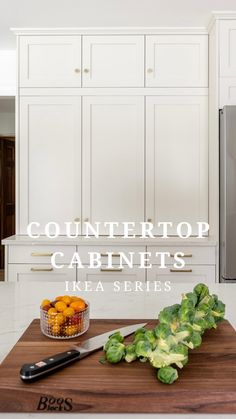 a kitchen with white cabinets and vegetables on the cutting board next to a black knife