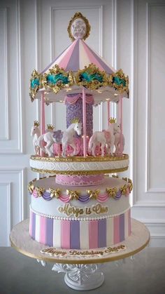 a three tiered carousel cake with pink, white and blue icing