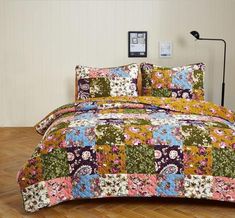 a bed covered in a colorful patchwork comforter and pillow case with matching pillows