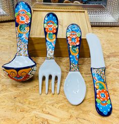 five pieces of colorfully painted utensils and spoons on a wooden table