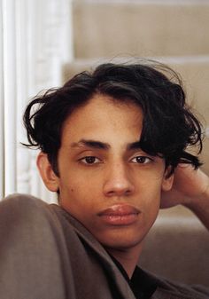 a young man sitting on top of a couch next to a white window sill