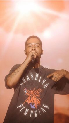 a man standing on top of a stage holding a microphone to his mouth with both hands