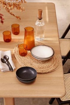 a wooden table topped with plates and bowls next to glasses on top of each other