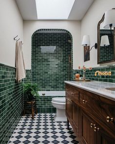 a bathroom with green and white tiles on the walls