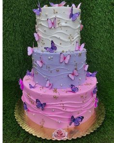 there is a multi layer cake with butterflies on the top and bottom, in pastel colors