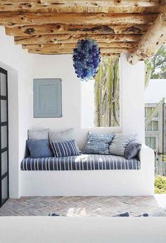 a white couch sitting under a wooden beam on top of a porch next to a window