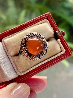 Here is a highly collectible  English Arts and Crafts Carnelian ring, modeled in sterling silver. Jewelry from the English arts and crafts movement typically invoked nature in all of its colors. In this lovely example, an organic, open work, flower motif accented with yellow gold detail, surrounds the firey Carnelian cabochon. The setting splits at the shoulders and then returns to a single band at the base.  What a wonderful gift for a collector or for your own antique jewelry collection. Size English Arts And Crafts, Carnelian Ring, English Art, Flower Motif, Arts And Crafts Movement, Gold Accent, Gold Details, Rings Statement, Gold Accents