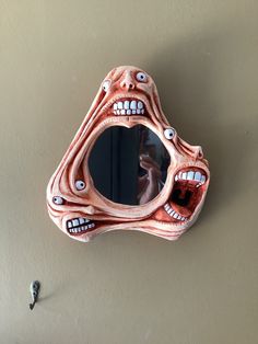 a mirror that is hanging on the side of a wall with fake teeth and eyes