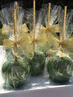 green apples wrapped in cellophane and tied with gold ribbon, sitting on a table