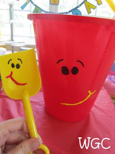 a person holding a plastic cup with a smiley face on it and a straw in the other hand