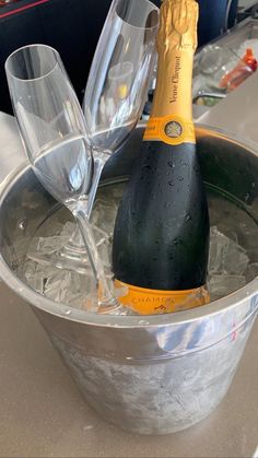 a bottle of champagne and two wine glasses in an ice bucket