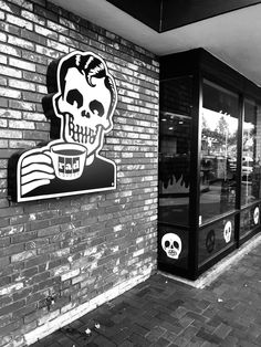 a black and white photo of a brick building with a sign that says coffee skull