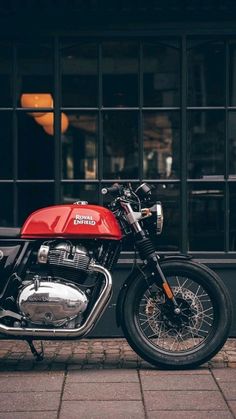 a red and black motorcycle parked on the side of a street next to a building