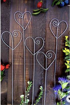 four metal hearts are arranged in the shape of flowers on a wooden table with other flowers