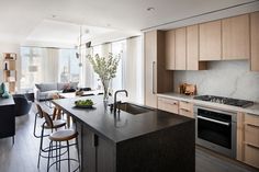 a kitchen and living room are shown in this modern style apartment with wood cabinets, marble counter tops, and stainless steel appliances