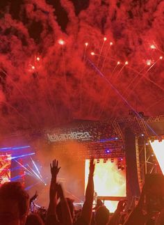 fireworks are lit up in the night sky above a crowd at an outdoor music festival