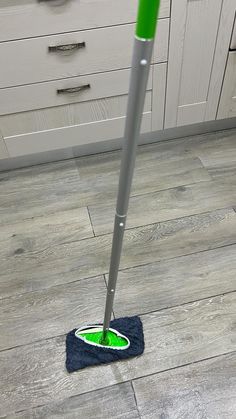 a mop on the floor with a green handle