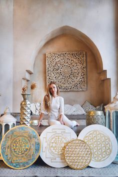 a woman sitting on the floor in front of some decorative plates and vases,