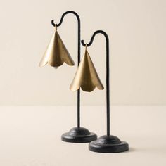 two brass - plated metal lamps on black stands, one is turned upside down