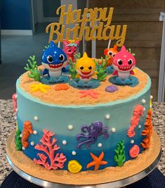 a birthday cake decorated with sea animals and under the sea theme is displayed on a table