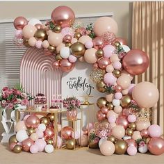 a pink and gold birthday party with balloons on the wall, cake table and decorations