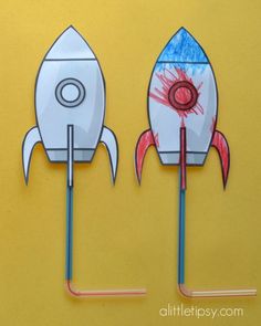 two paper rockets are on sticks with colored crayons